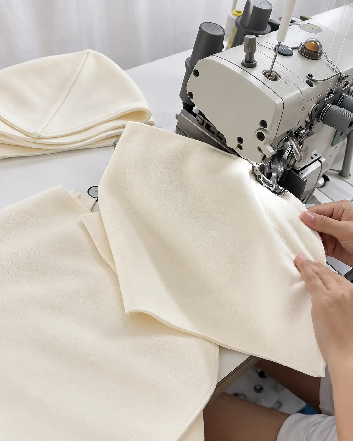 Curved cream hood panel being sewn at a sewing machine