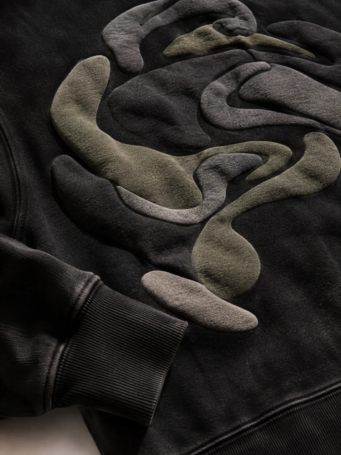 Close-up of a dimensional abstract puff print on washed black fabric